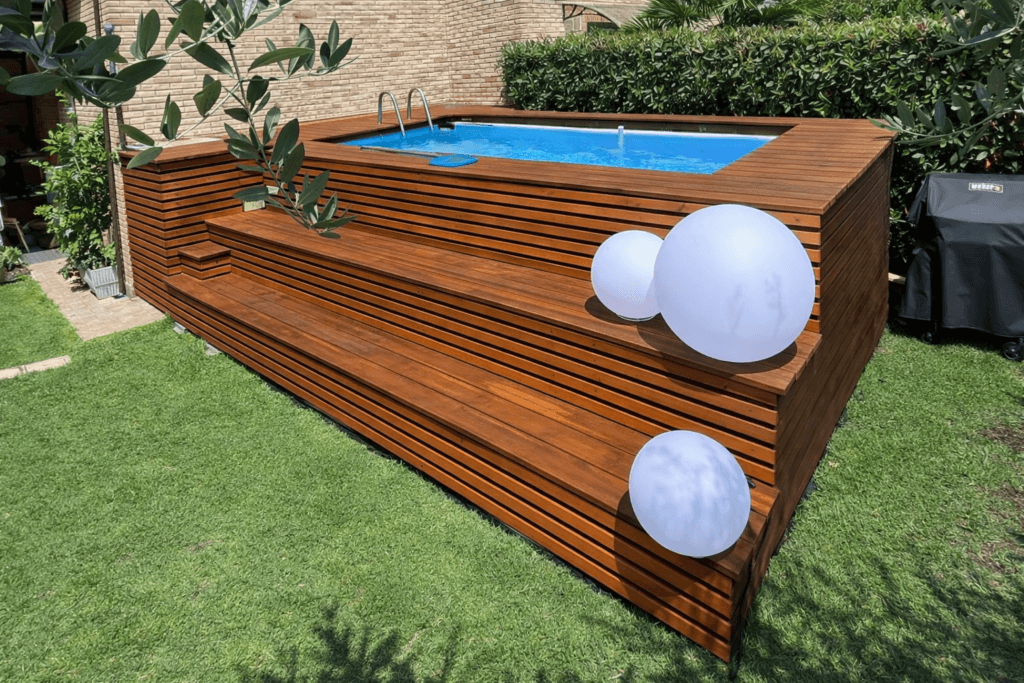 Solarium in legno su misura per piscina fuori terra con gradoni integrati, realizzato da Skenarte per rivestimento estetico e funzionale in giardino